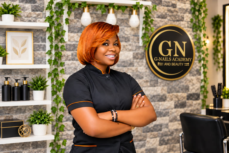 Formatrice en tenue noire devant l’enseigne G-Nails Academy, dans l’espace de formation.